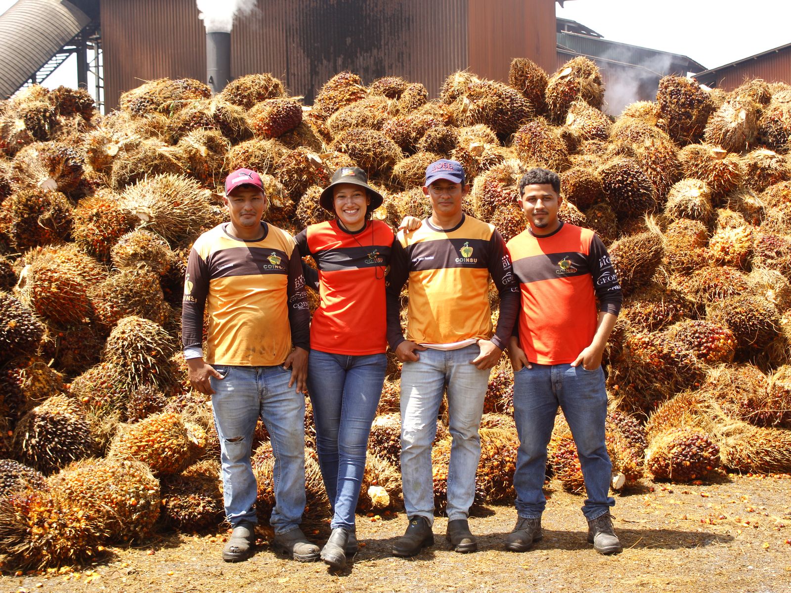 Equipo de COINSU frente a racimos de palma aceitera