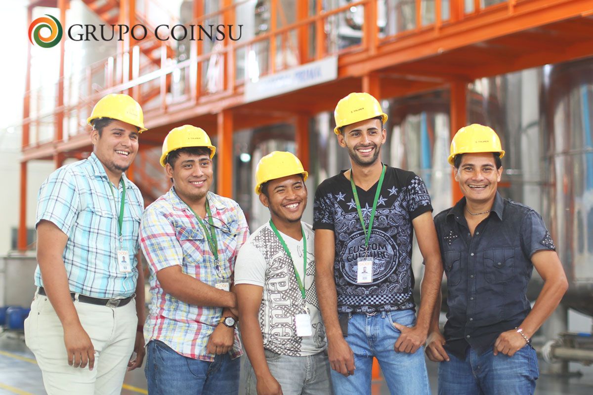 Equipo de colaboradores de GRUPO COINSU con cascos, orgullosos frente a su planta